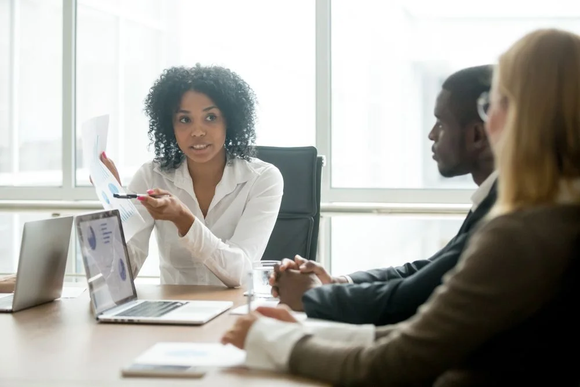 A woman is giving a presentation to a group of people at a conference table.