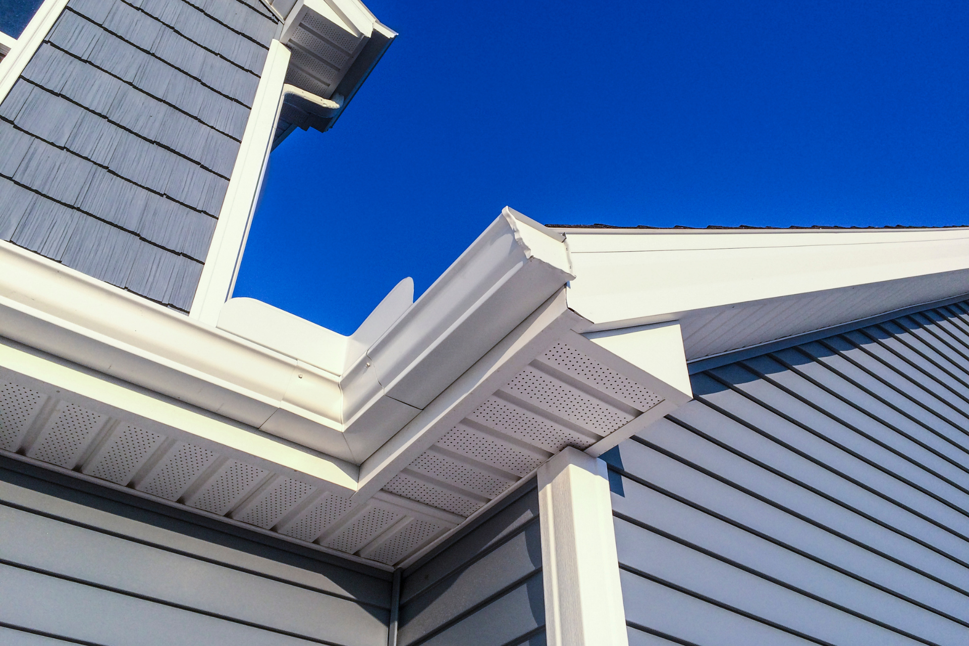 a house with a white gutter and a blue sky in the background.