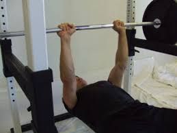 A man is laying on a bench holding a barbell over his head.