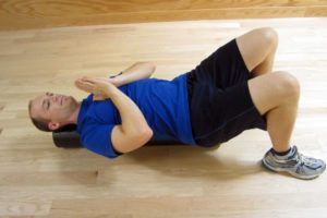 A man is laying on the floor using a foam roller.