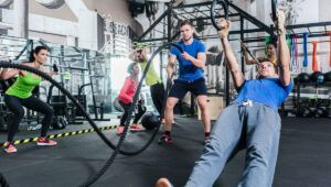 A group of people are doing exercises with ropes in a gym.