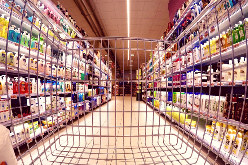 A shopping cart is empty in a supermarket aisle.