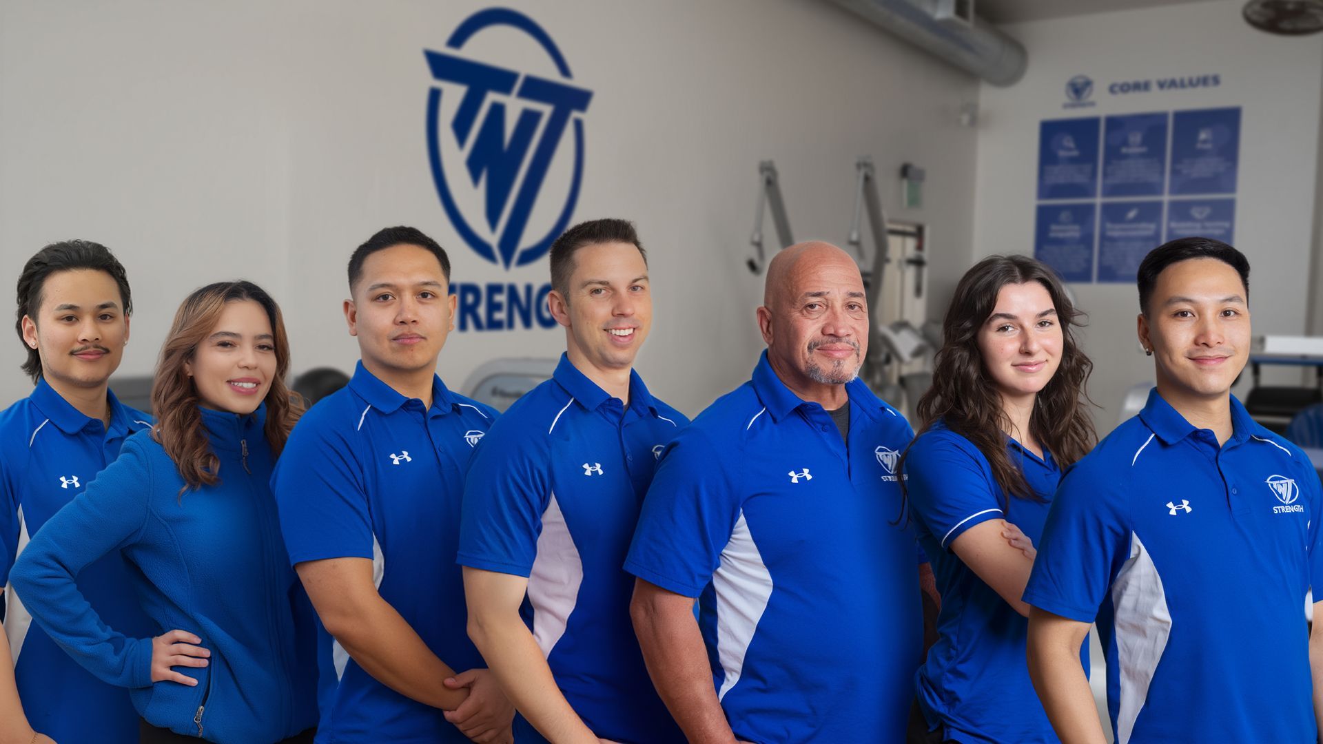 TNT Strength Coaches four in TNT Strength blue jackets standing next to each other.