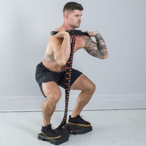 A man is squatting with a resistance band around his waist.