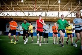 A group of people are running on a field in a gym.