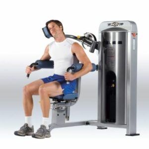 A man is sitting on a machine in a gym