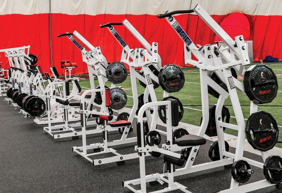A row of exercise machines are lined up in a gym.