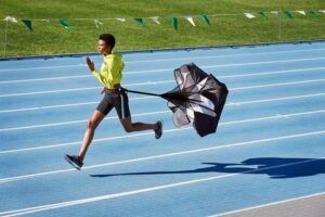 A man is running on a track with a parachute attached to him.