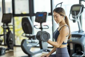 A woman is lifting a dumbbell in a gym.
