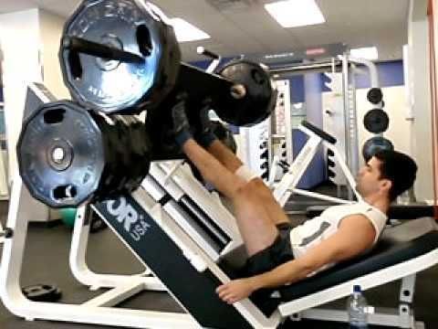 A man is using a leg press machine in a gym.