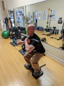A man is squatting with a barbell in a gym.