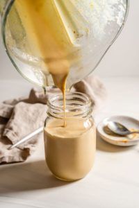 A jar of sauce is being poured from a blender into a jar.