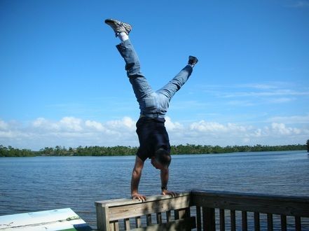 A man is doing a handstand in front of a body of water