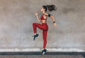 A woman in red sportswear is jumping in the air.