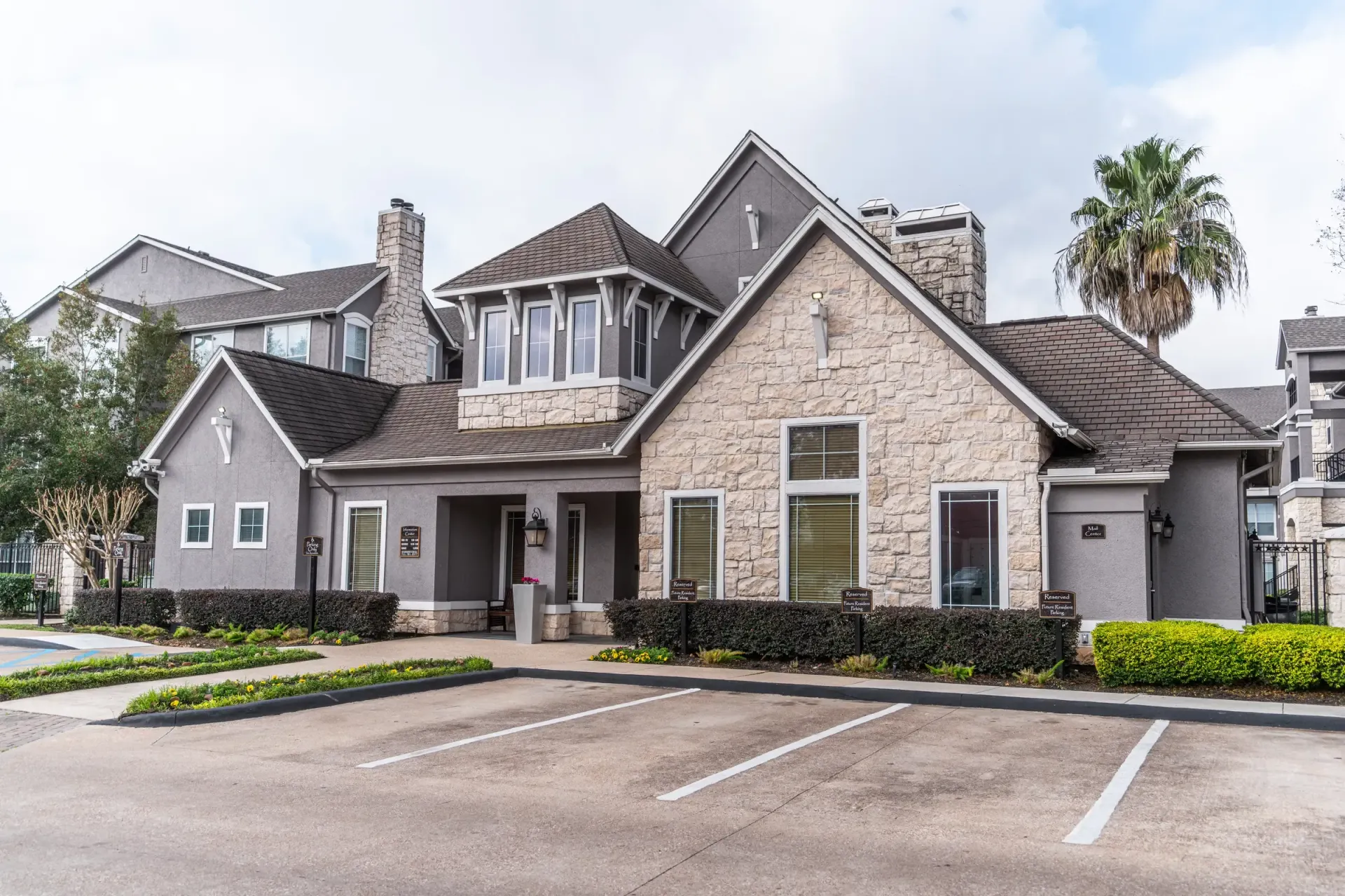 Stone and gray building with a brown roof and a few parking spaces in front.