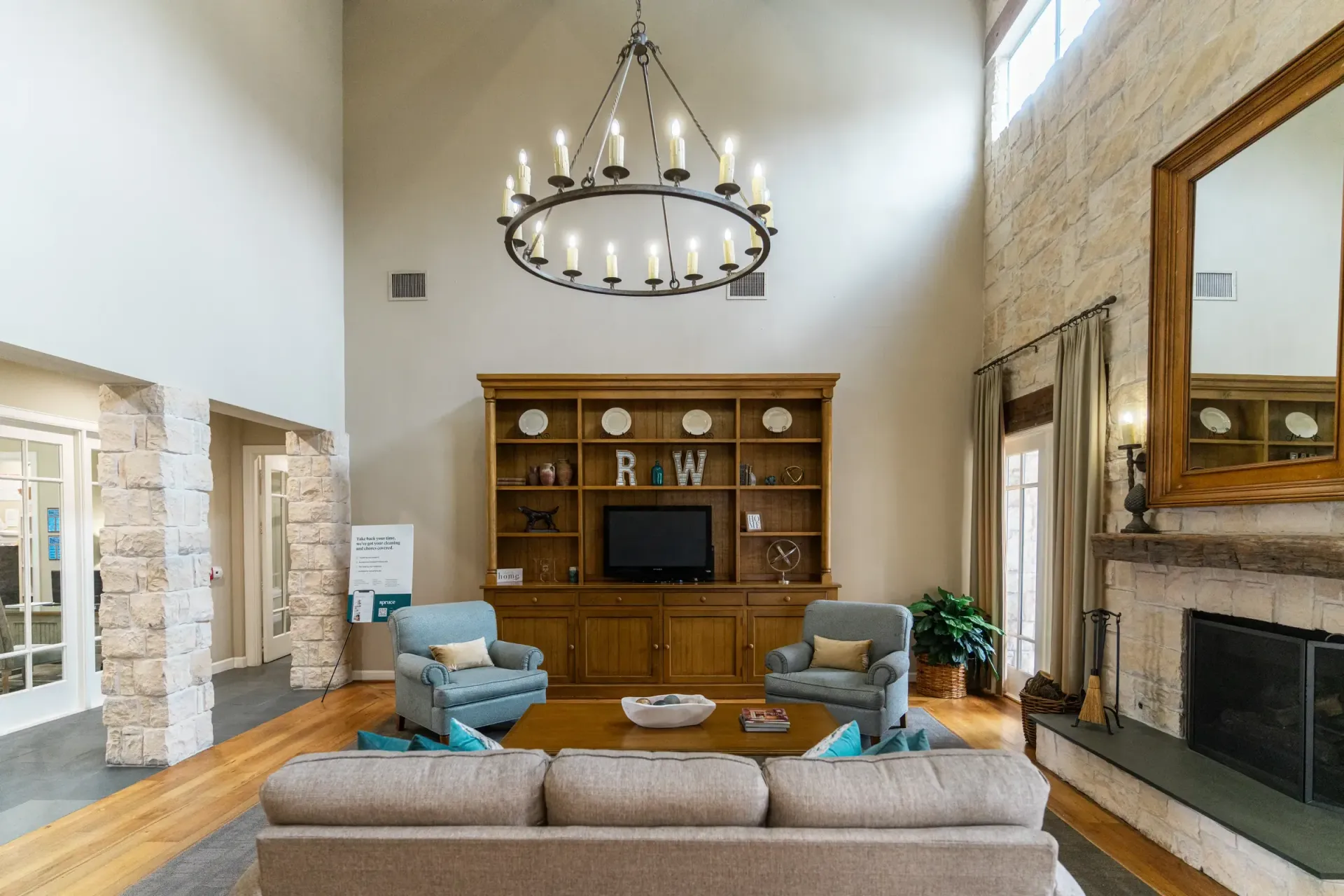 Lobby with high ceiling, fireplace, wooden bookshelf, seating, and a chandelier.