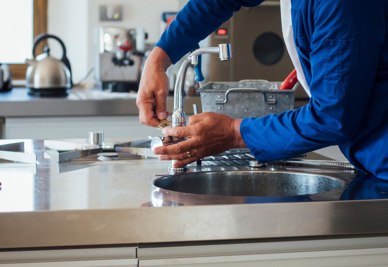 A man is fixing a sink in a kitchen.