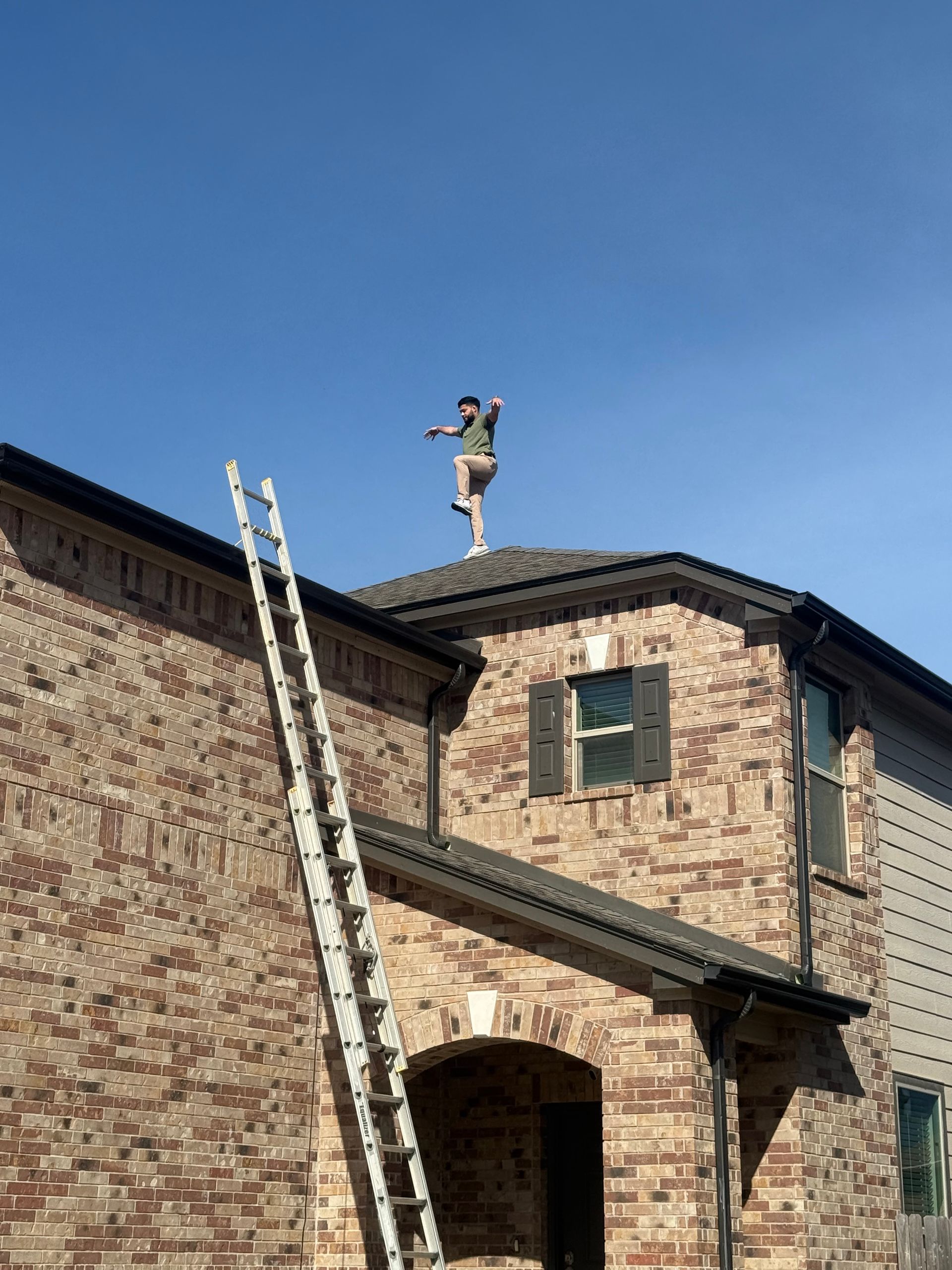 Brick house with a ladder leaning to the roof under a clear blue sky