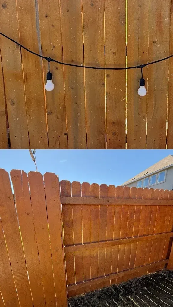 Wooden backyard fence with two hanging string lights against a cloudy sky