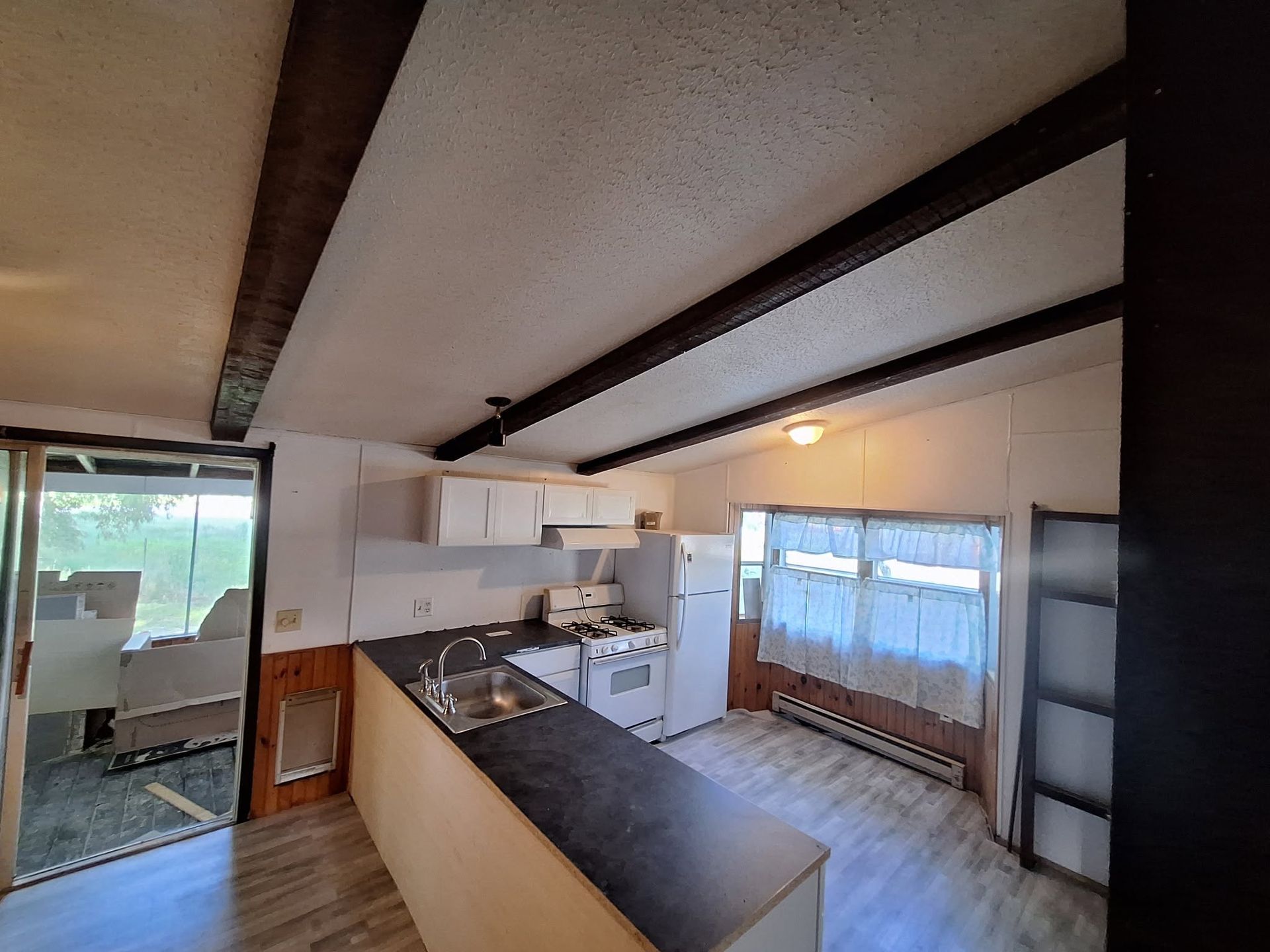 Small kitchen with black countertop, white cabinets, and sliding glass doors to a patio.