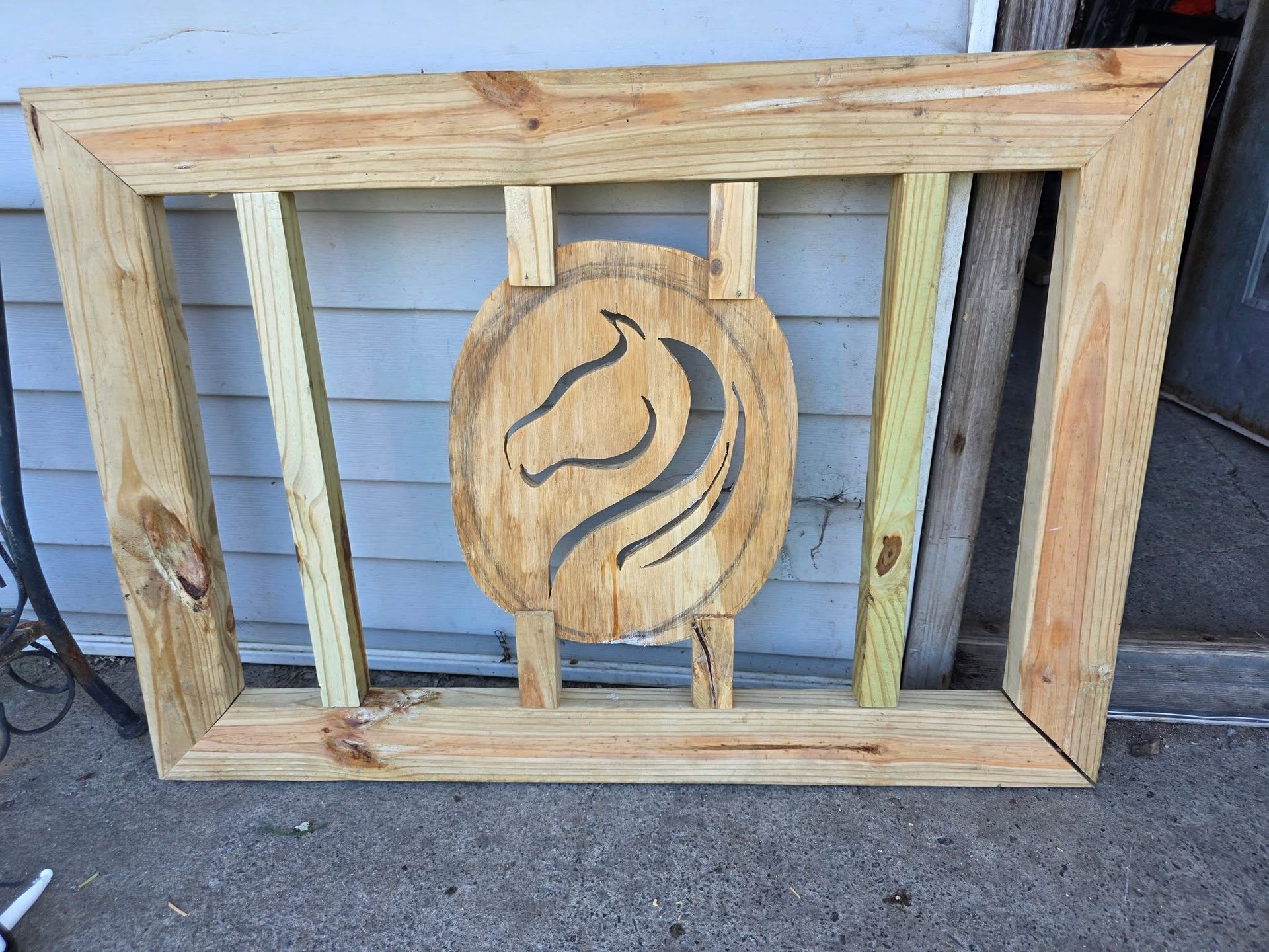Wooden framed wall art with vertical slats and a carved circular swirl design on a porch wall