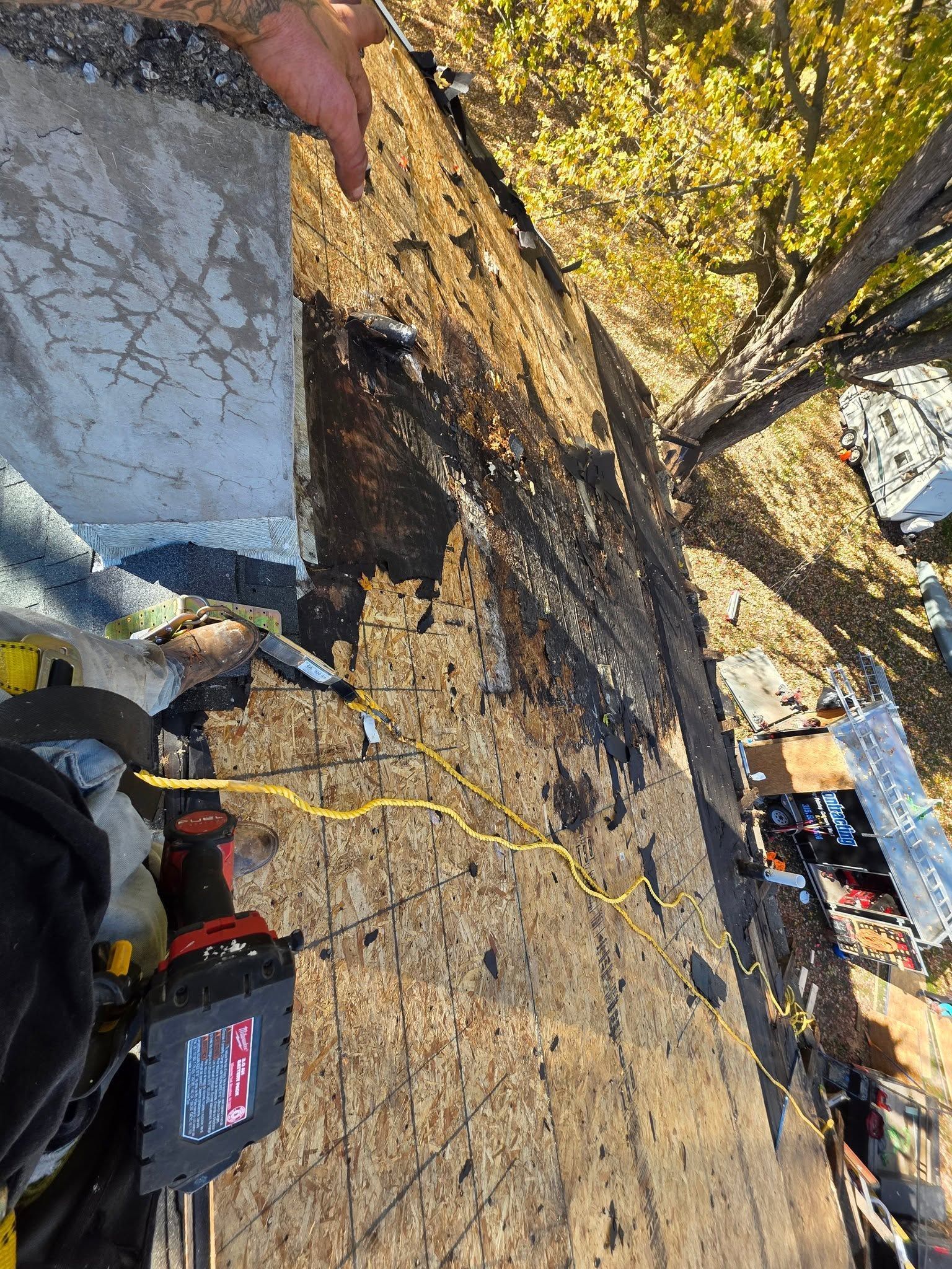 Roof repair scene with tools on a sloped rooftop near trees and a house below
