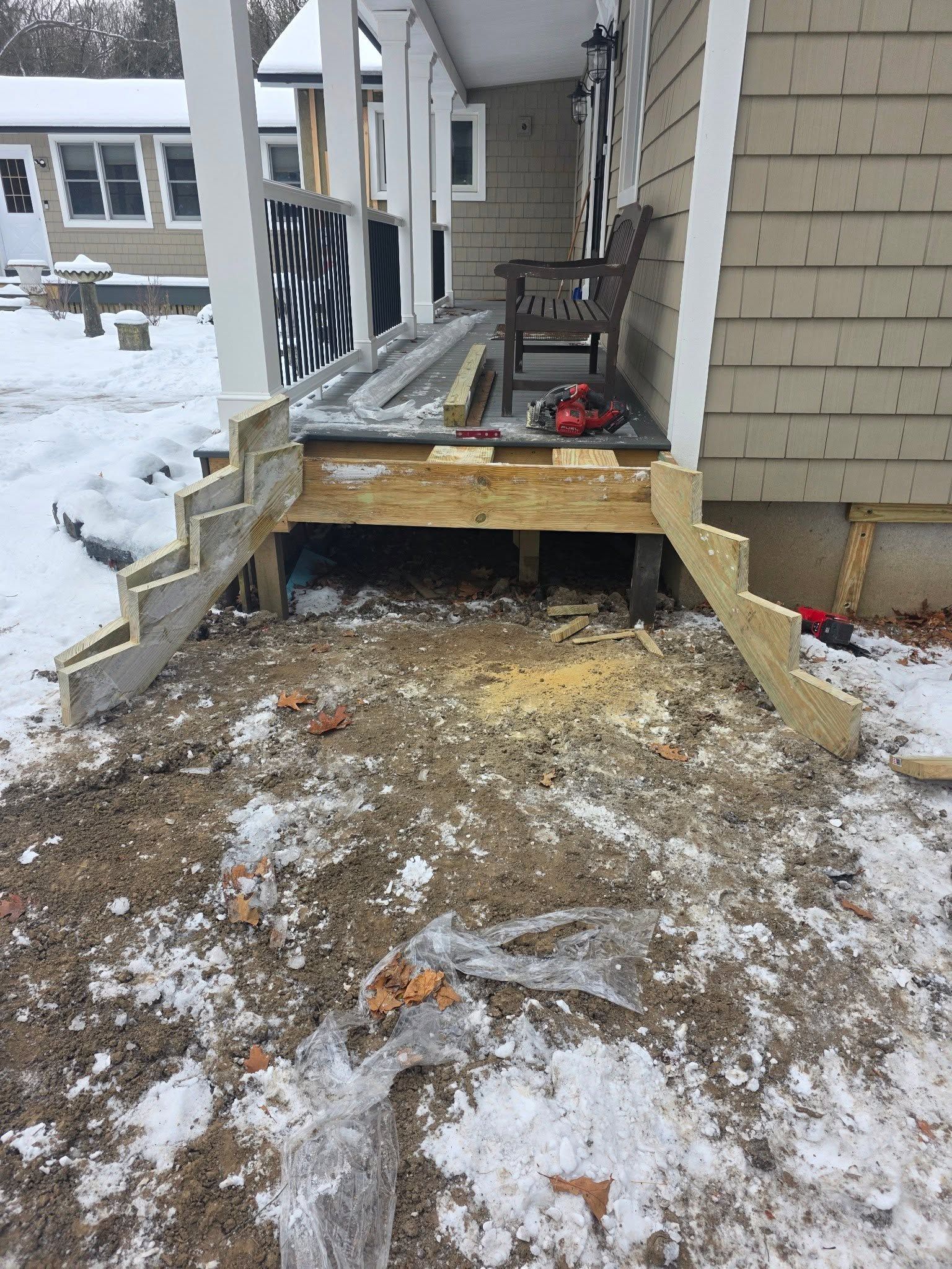 Collapsed front porch with exposed wooden supports, snow, and debris outside a house