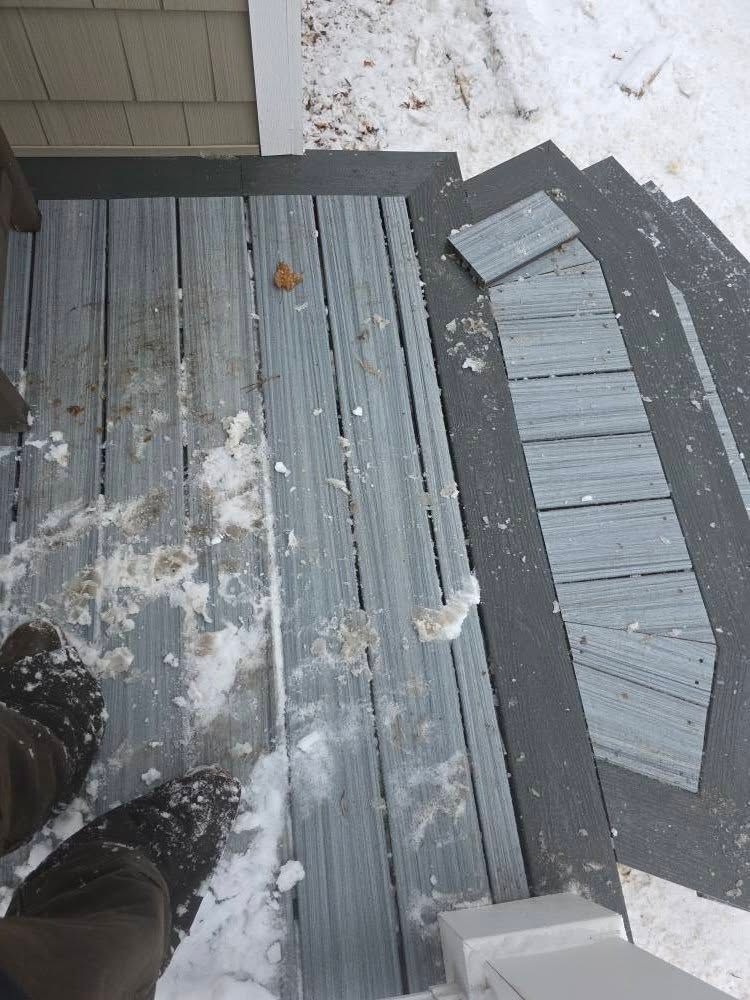 Snow-covered porch steps with gray boards and a person’s boots at the bottom edge