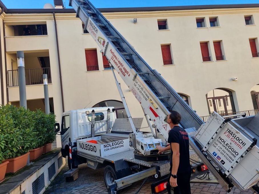 Autoscala estesa accanto a un edificio, con un vigile del fuoco in piedi vicino alla base.