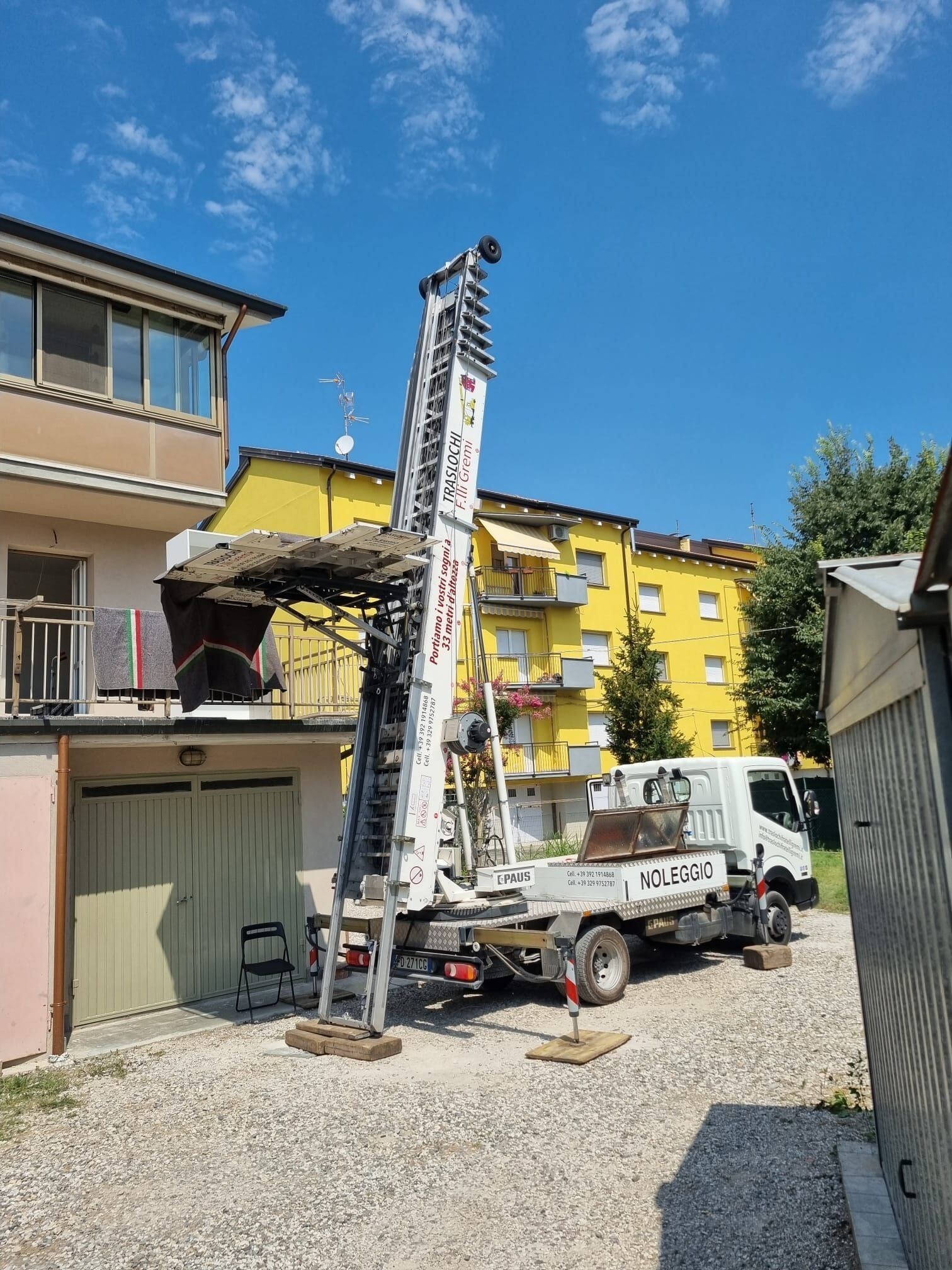 Camion trivellatore e trivella ad alta capacità in un cantiere edile accanto a palazzine gialle.