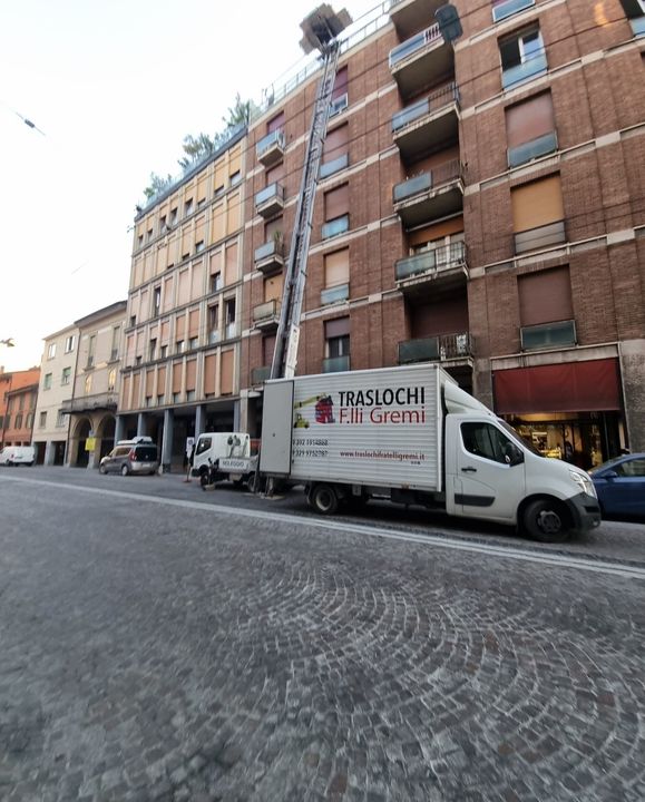 Un furgone bianco per le consegne su una strada acciottolata accanto ad alti palazzi in una città.