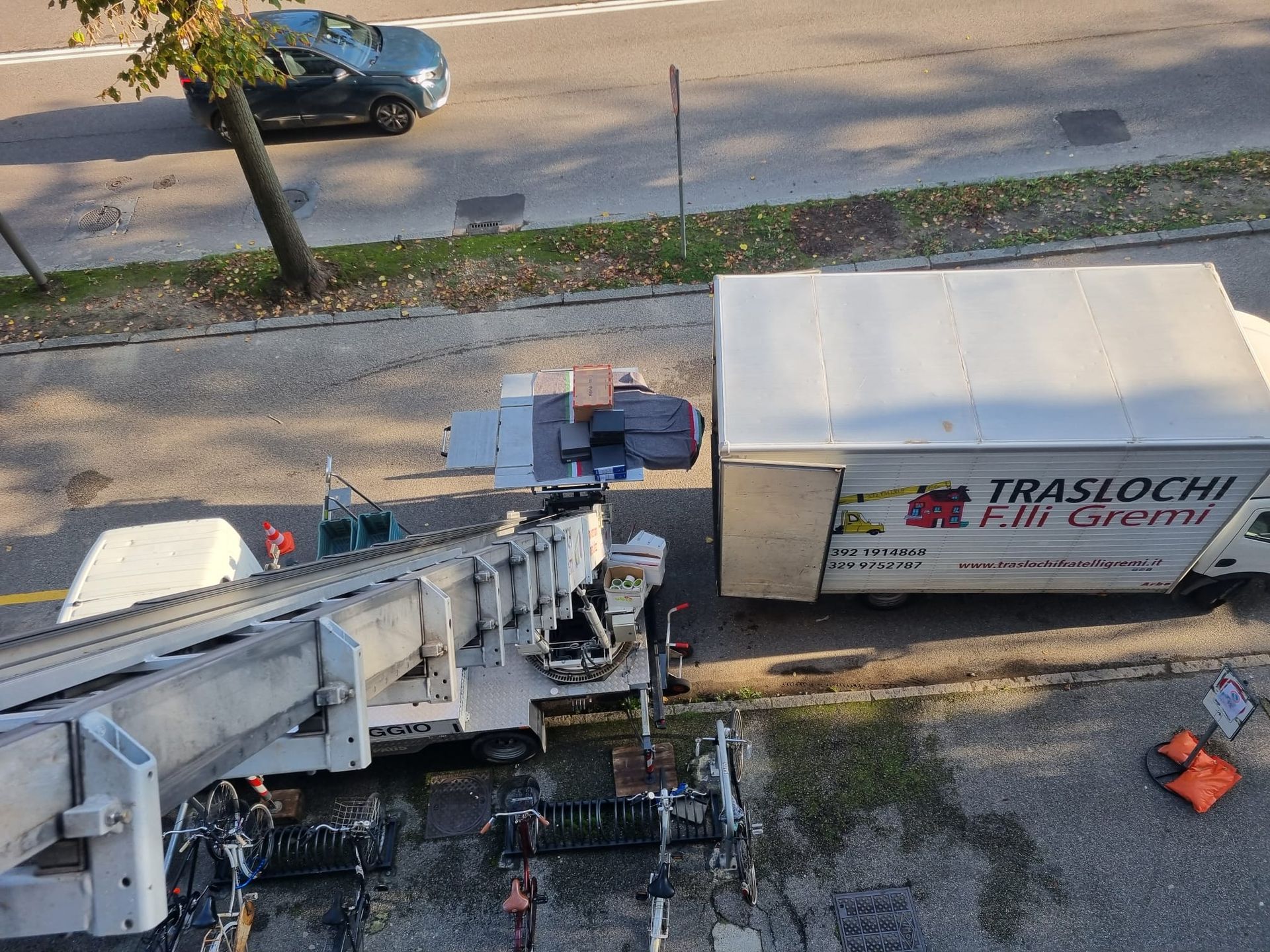 Veduta aerea di un camion bianco che carica un rimorchio TIR parcheggiato a lato della strada.