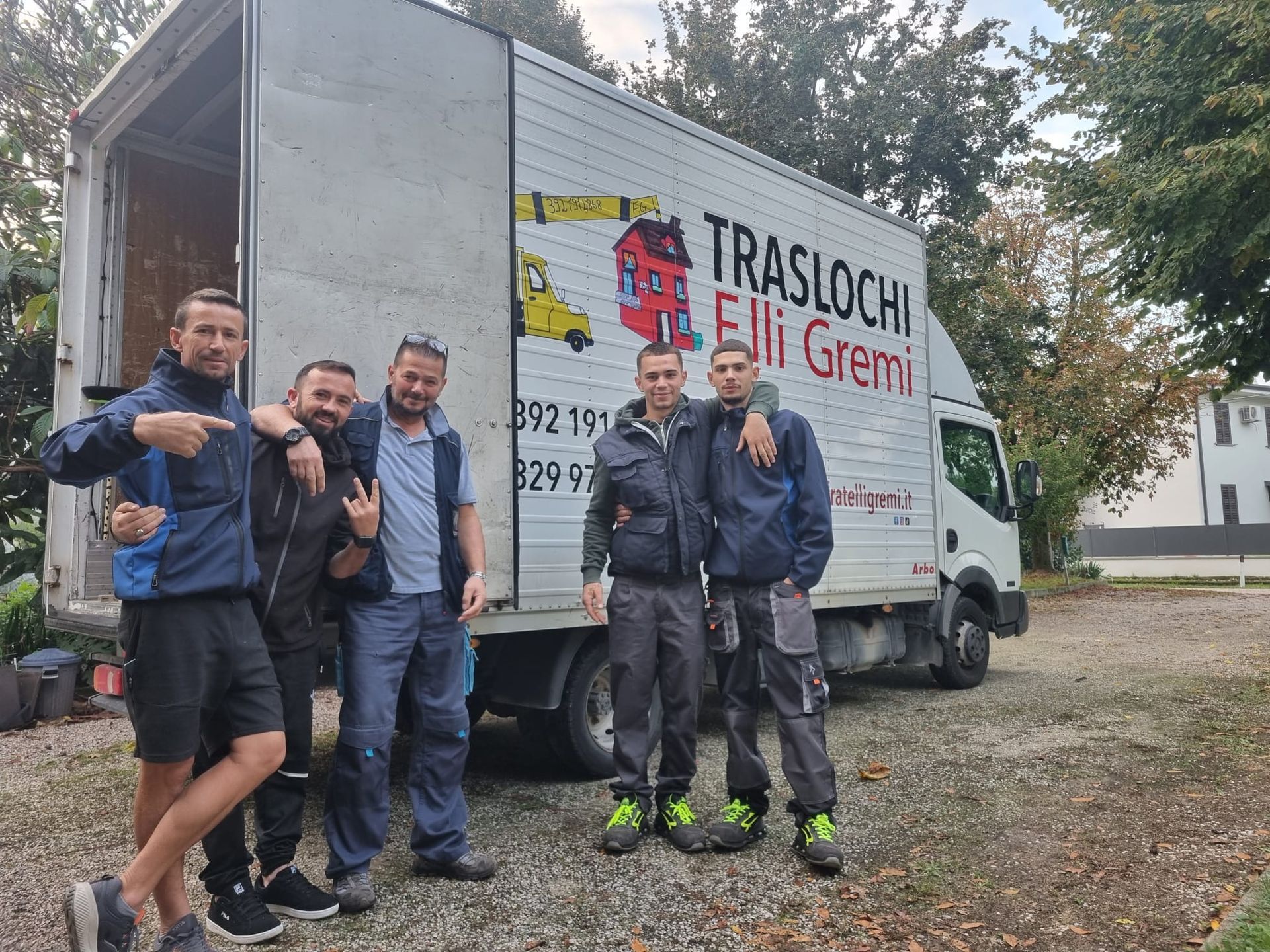 Cinque uomini in posa accanto a un camion bianco per traslochi con la scritta