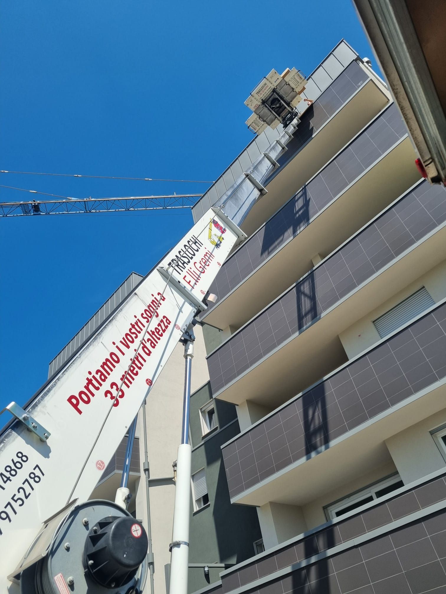 Alto palazzo residenziale con una gru e un cartello rosso francese da cantiere sullo sfondo di un cielo azzurro.