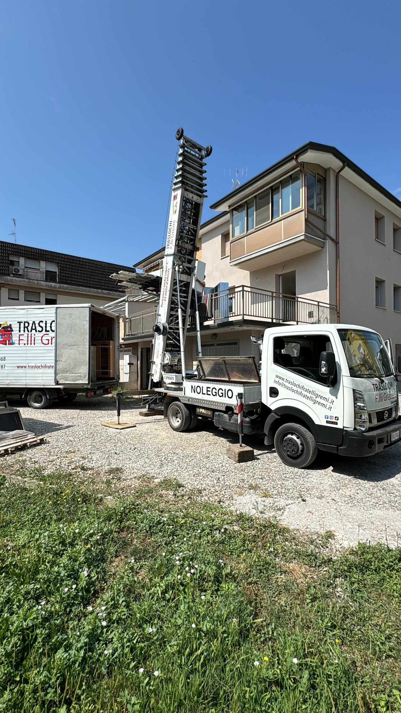 Un camion trivellatore accanto a una casa beige su un terreno ghiaioso sotto un cielo azzurro e limpido.