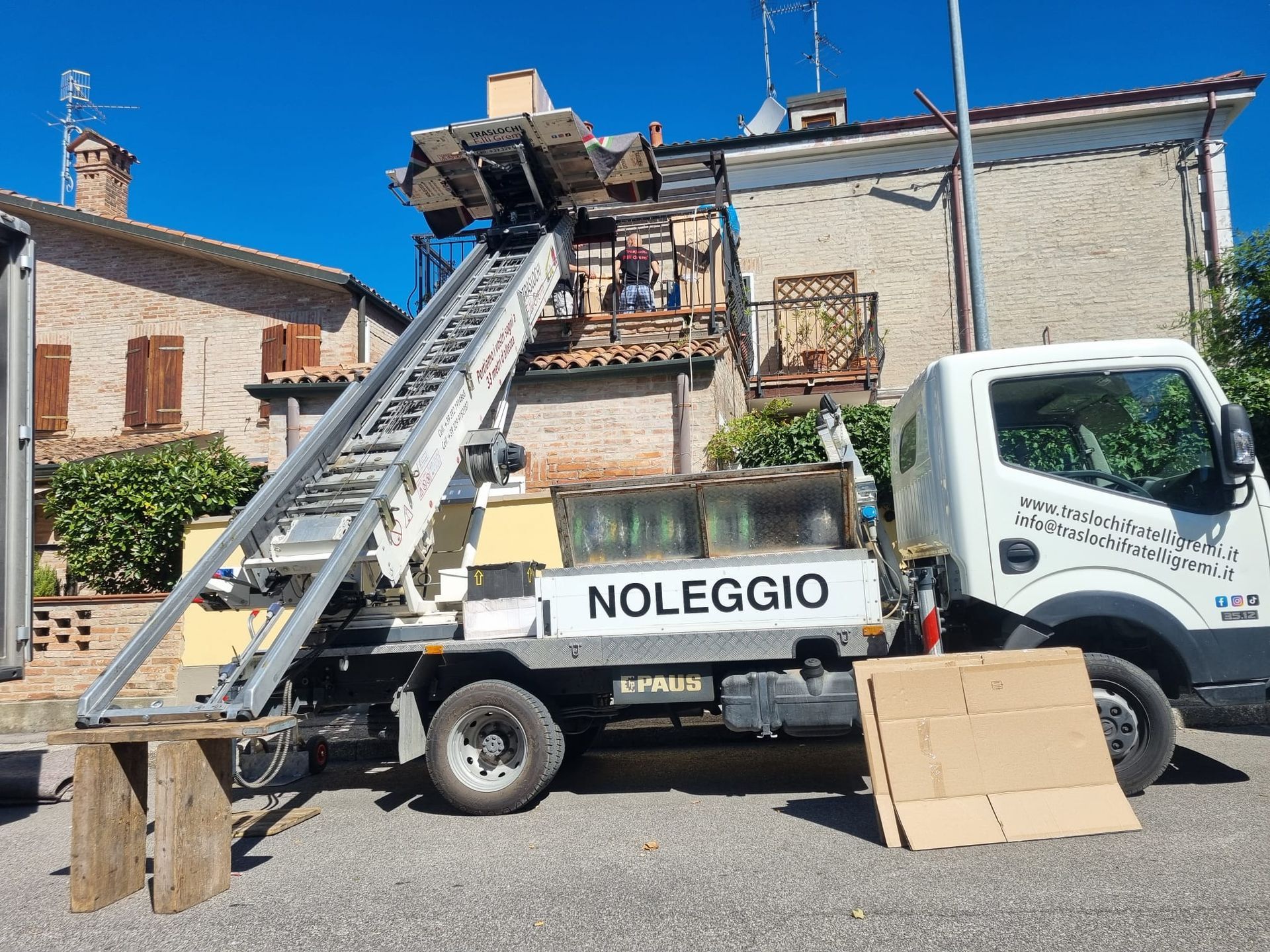 Carrello elevatore a noleggio con scala sollevata fino al cantiere sul tetto di una casa, con la scritta