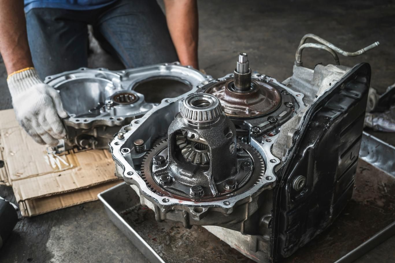 A Man Is Working on A Car Transmission in A Garage — Envy Automotive in Gorokan, NSW