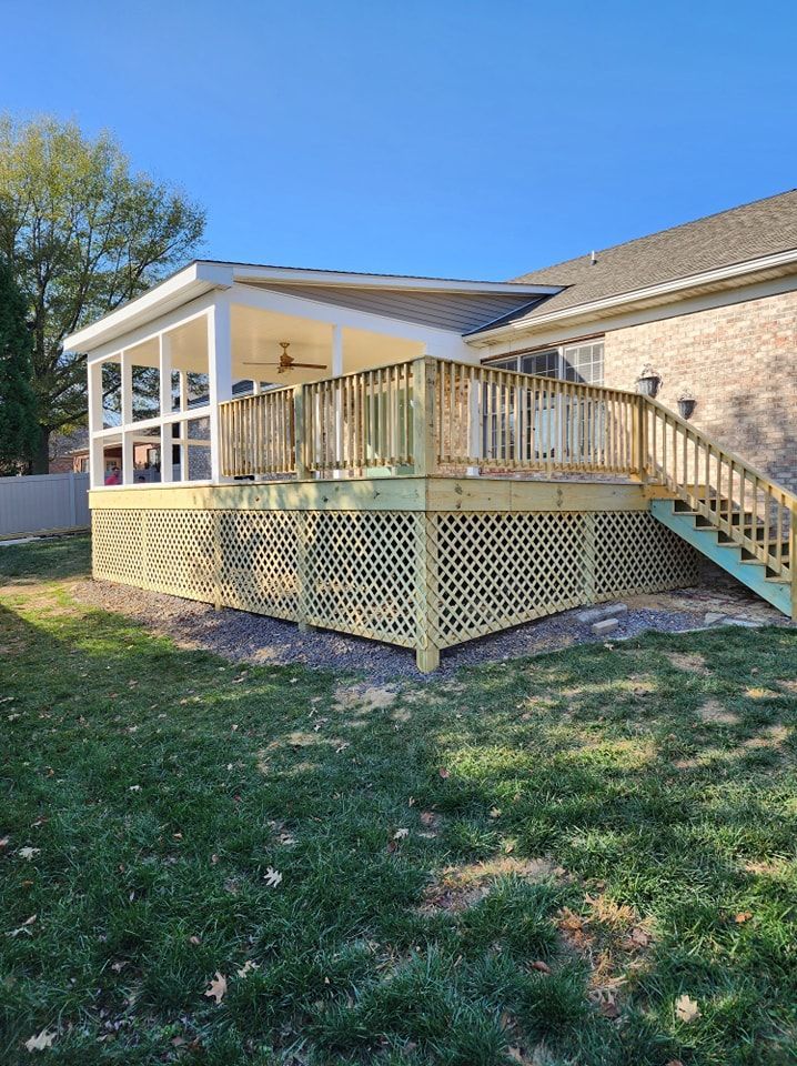 Wooden deck with lattice skirting, attached to a house with a screened porch and stairs, on green grass.