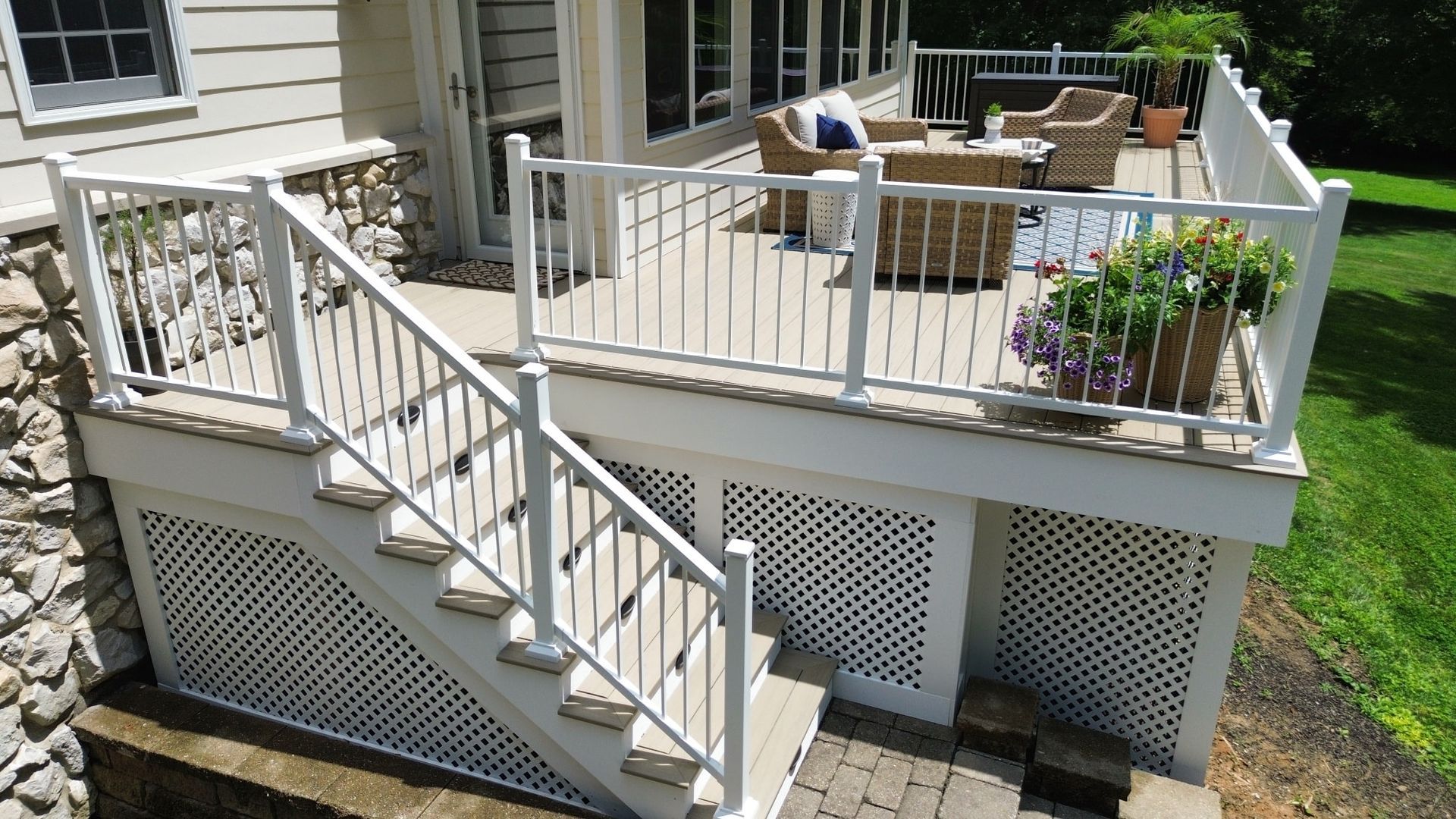 White deck with stairs, lattice skirting, and outdoor seating on a sunny day.