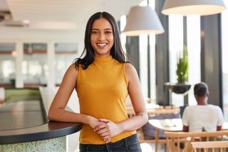 Woman smiling, leaning on a dark counter in a modern, 