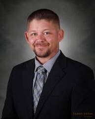 Man in a suit smiles, looking at the camera.