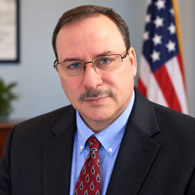 A man in a suit and tie is sitting in an office chair.