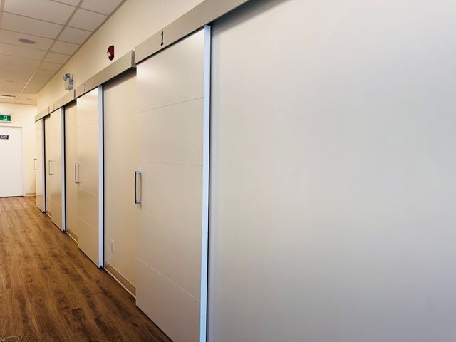 Empty office hallway with closed sliding doors and wood flooring