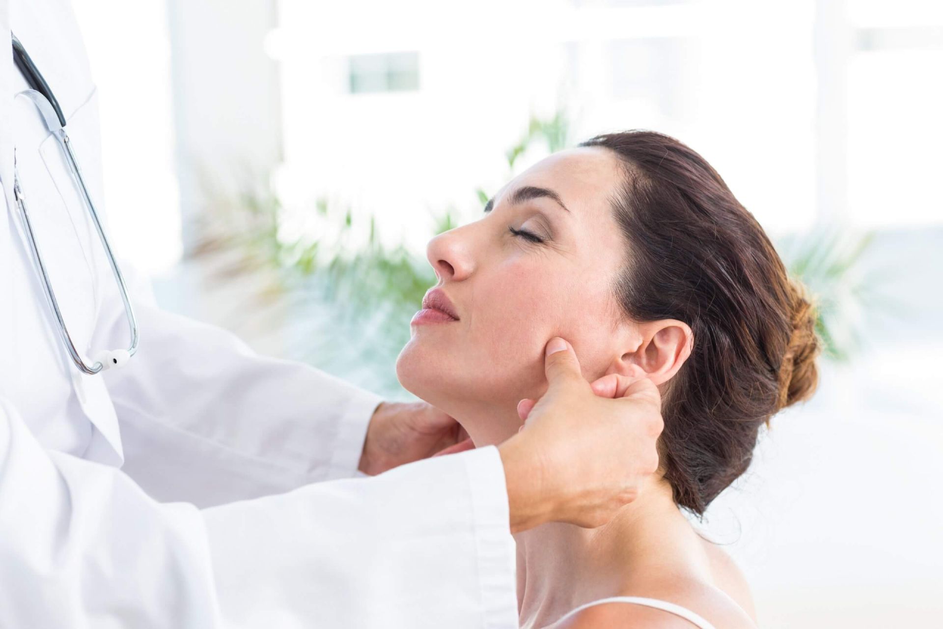 A woman is getting her neck examined by a doctor.