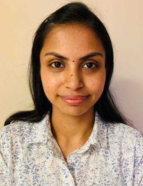 A woman wearing a floral shirt is smiling for the camera.