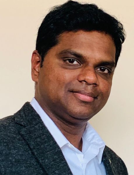 A man in a suit and white shirt is smiling for the camera.
