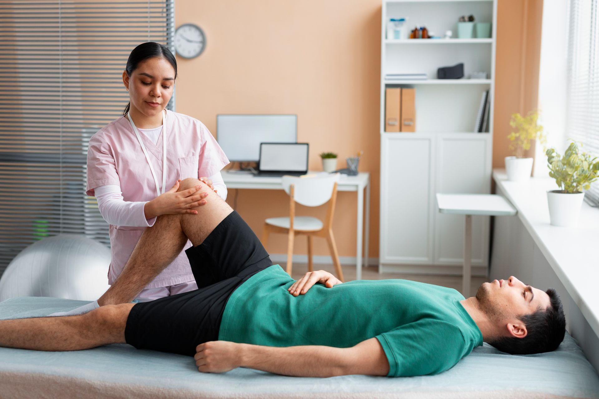 Physical therapist stretching a patient’s leg on a treatment table in a bright clinic room