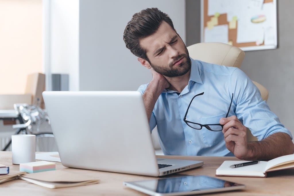 A man is sitting at a desk in front of a laptop computer.
