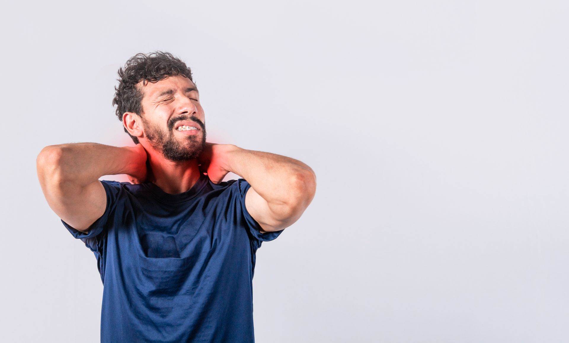 Man in navy shirt grimacing and holding his neck with a red towel around his shoulders