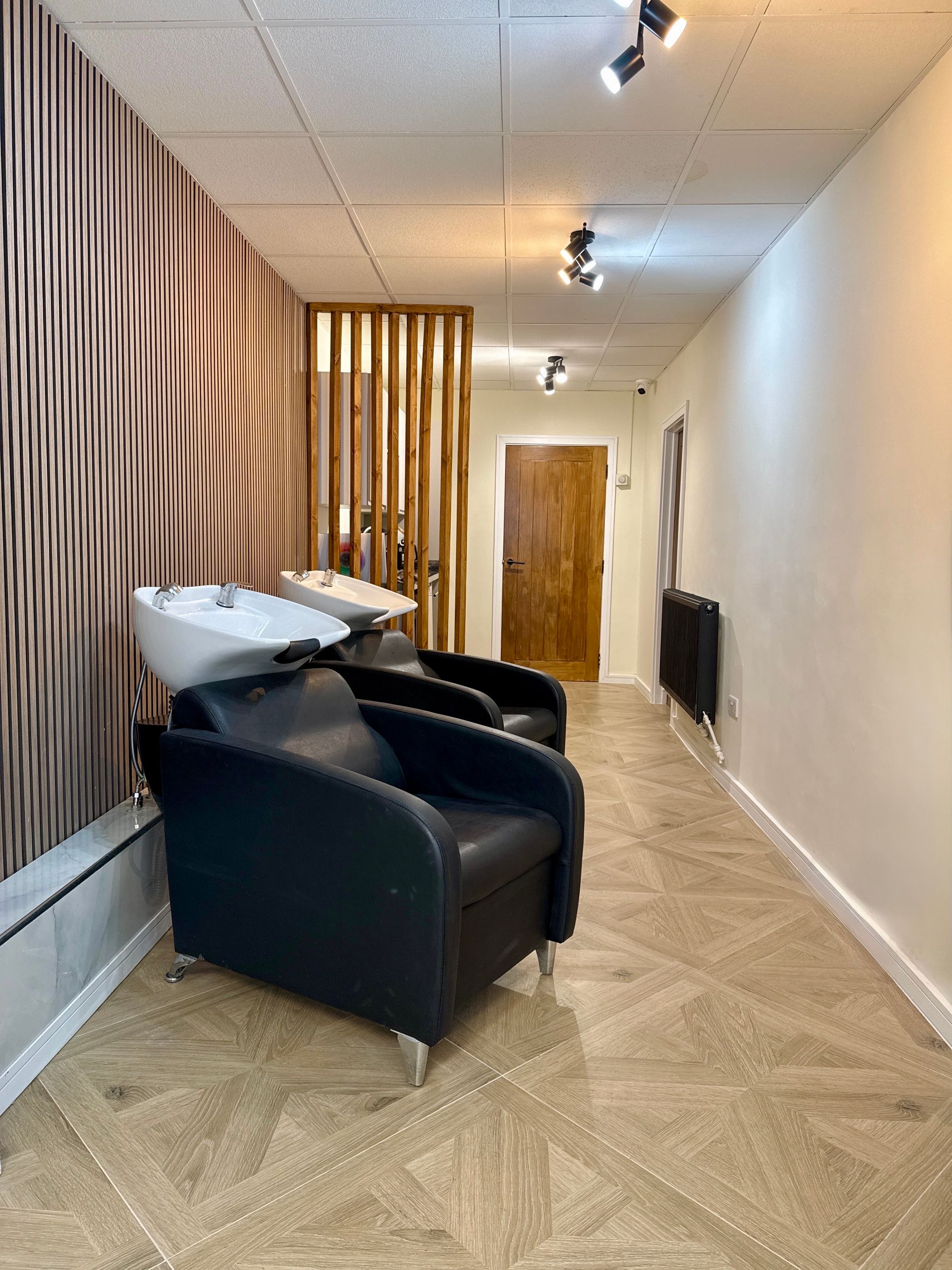 A long hallway with chairs and sinks in a hair salon.